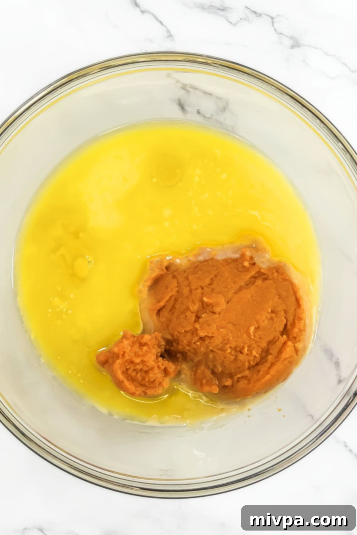 A glass bowl with pumpkin puree, melted butter and vanilla extract.