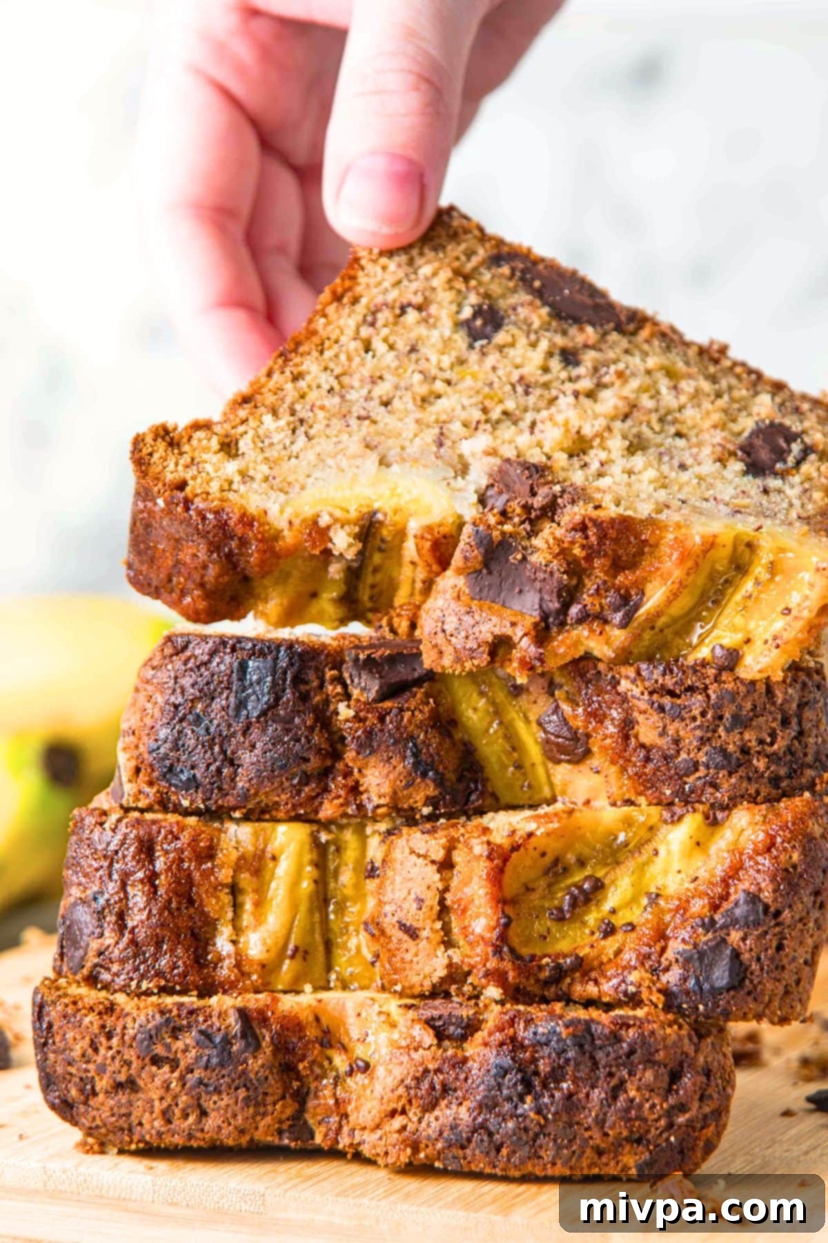 Reaching for a slice of banana bread in a stack of banana bread.