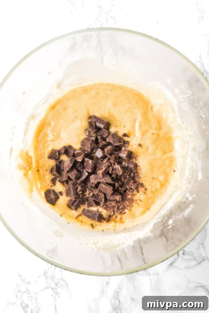 Chopped chocolate sprinkled on banana bread batter.