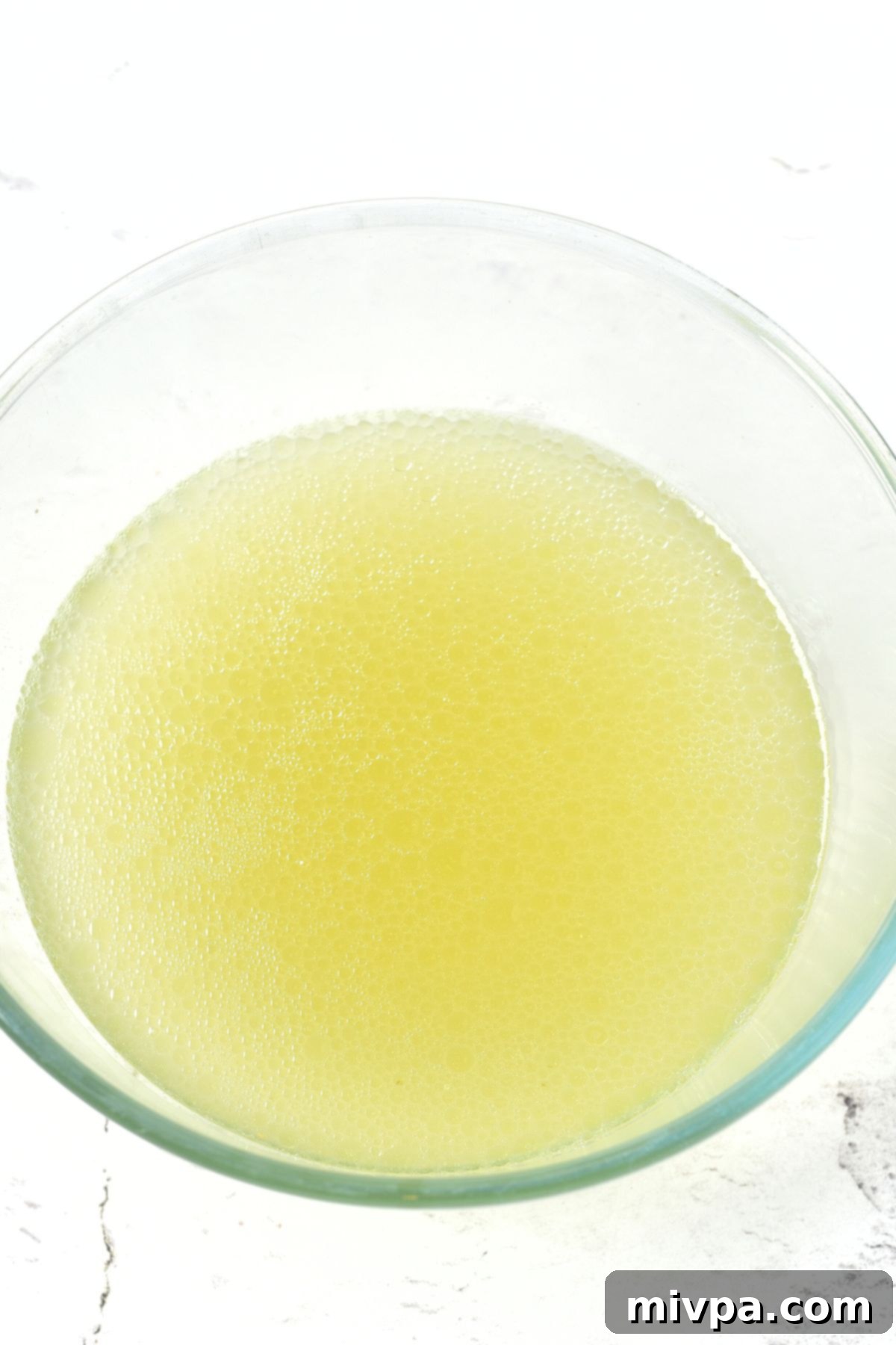A glass bowl of clear chicken broth.
