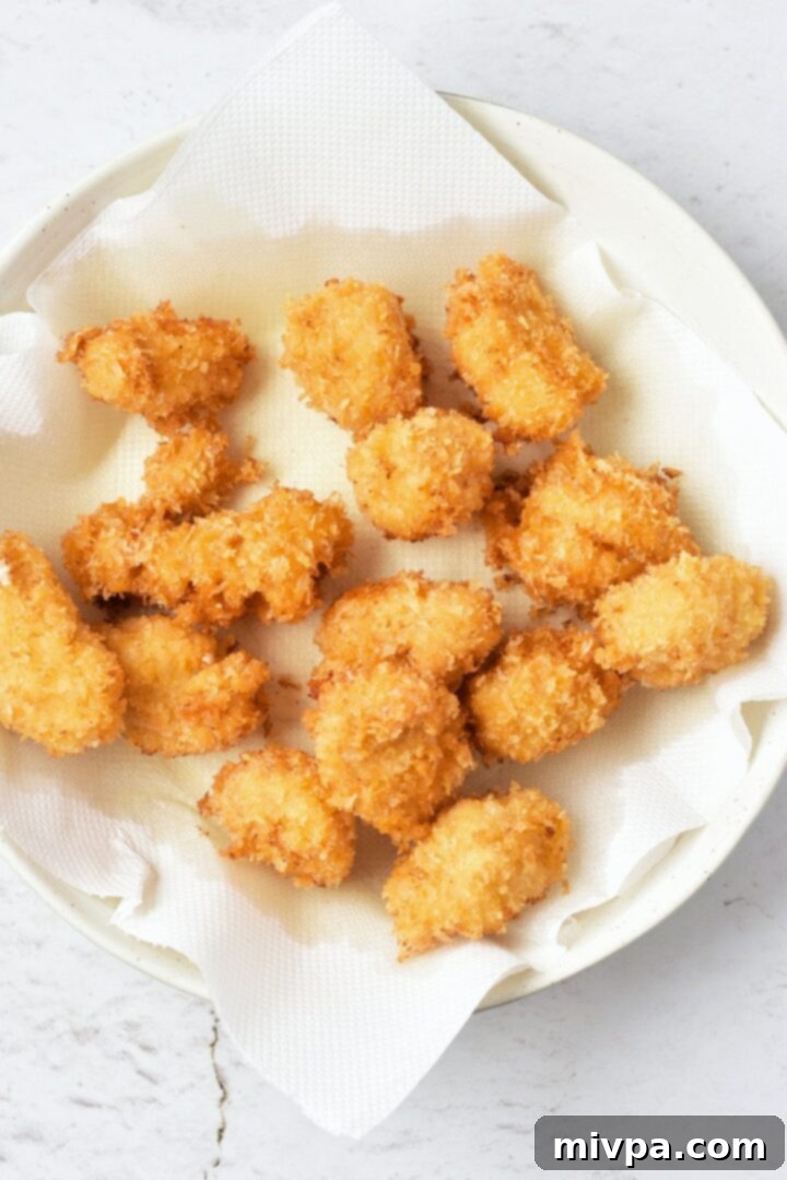 Crispy Gluten-Free Chicken Bites Freshly fried gluten-free chicken nuggets resting on a paper towel-lined plate to drain excess oil.