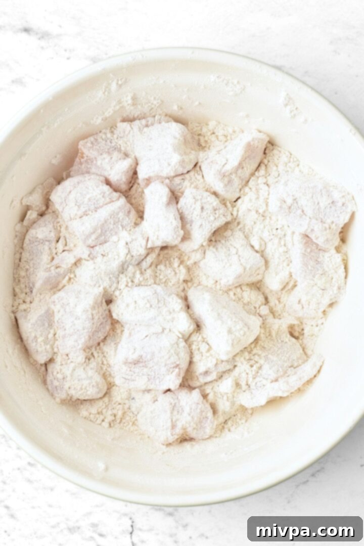 Recipe for Gluten-Free Chicken Nuggets Close-up of chicken cubes being coated in the gluten-free flour mixture in a bowl.