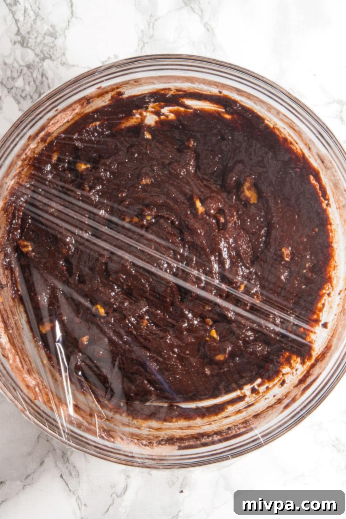 Chilling Gluten-Free Dairy-Free Walnut Chocolate Cookie Dough A bowl of chocolate cookie dough tightly wrapped in plastic wrap, chilling in the refrigerator.