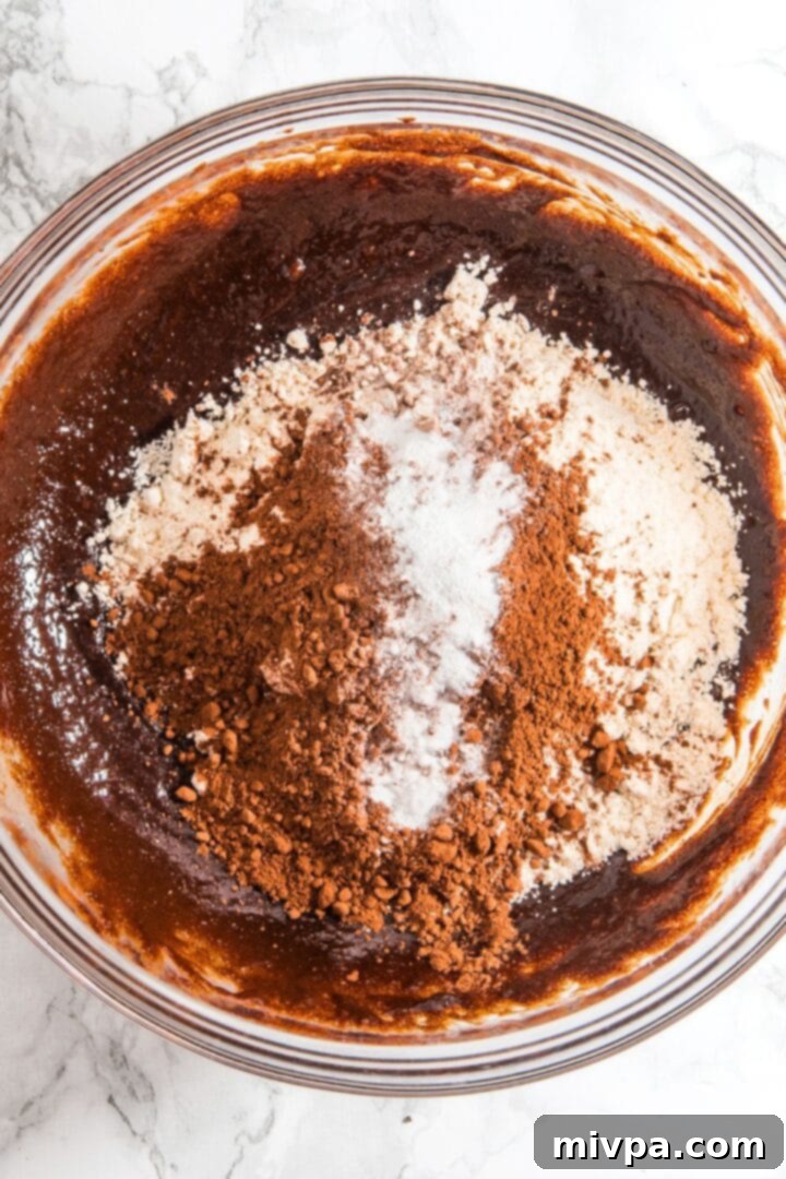Mixing Dry Ingredients for Chocolate Walnut Cookies Cocoa powder and gluten-free flour mixture being added to the rich chocolate base in a mixing bowl.
