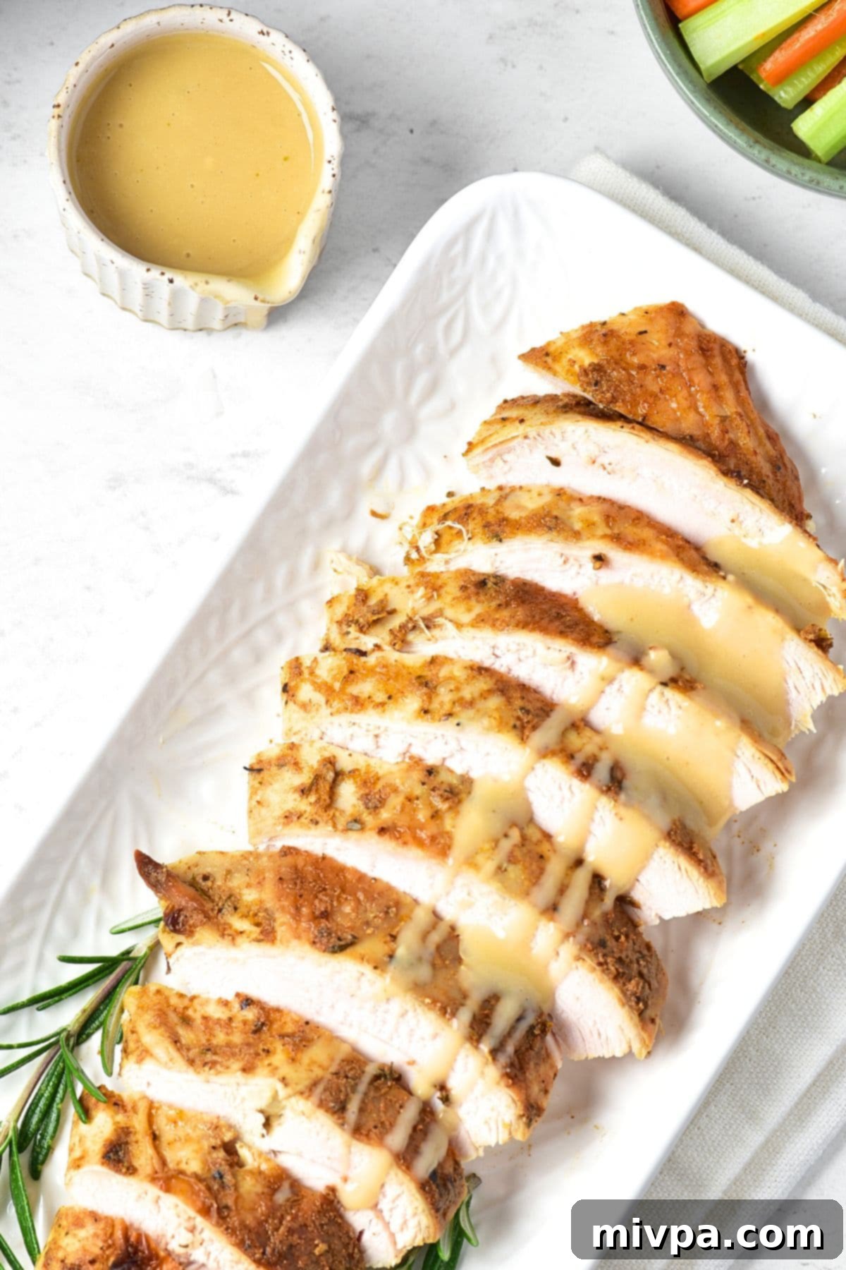 Turkey gravy drizzled over sliced turkey breast with rosemary sprigs