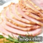 Up close view of sliced ham and fresh rosemary sprig