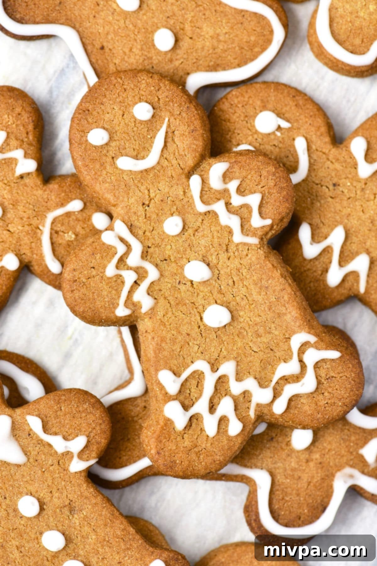 Easy Gluten-Free Gingerbread Men (Dairy-Free) Top down view of gluten-free gingerbread men on parchment paper, ready to be enjoyed.