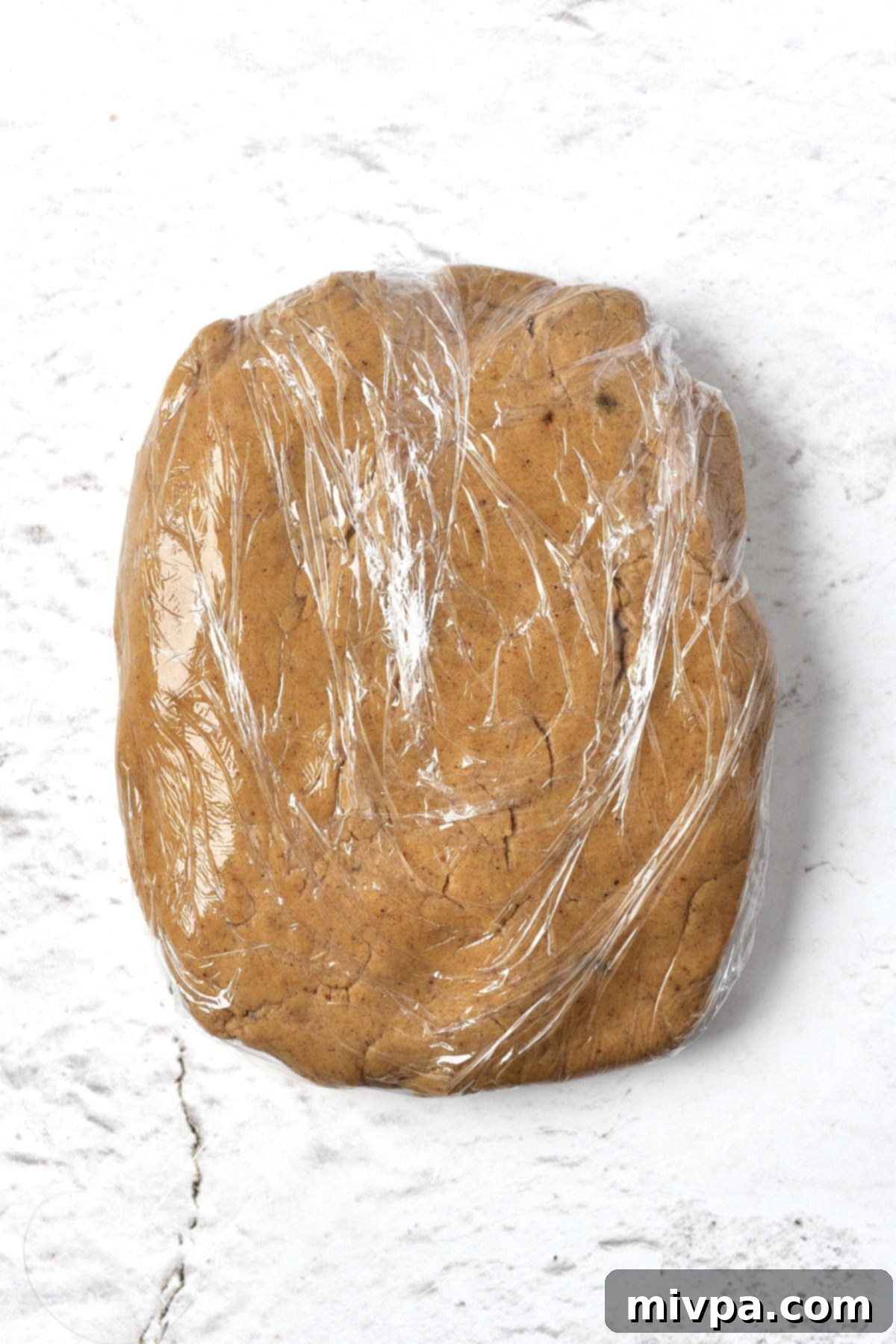 GF DF Gingerbread Men Brown cookie dough wrapped in plastic wrap, ready for chilling in the refrigerator.