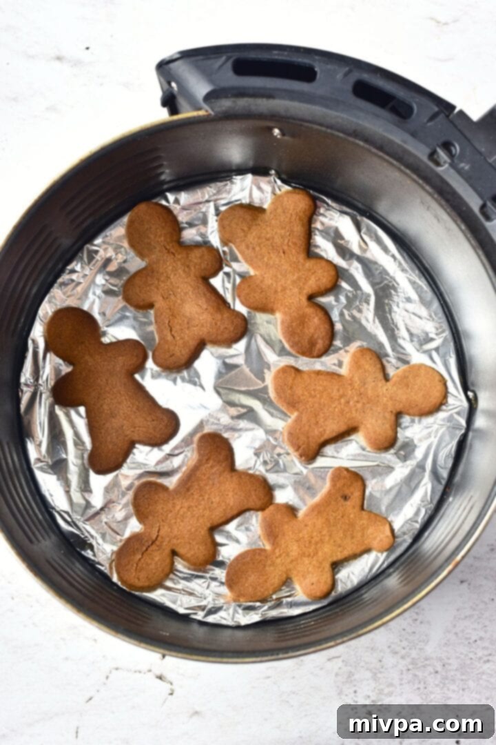 How to Make Gingerbread Men Cookies (Gluten-Free) Freshly baked gingerbread men cookies in air fryer basket, perfectly cooked.