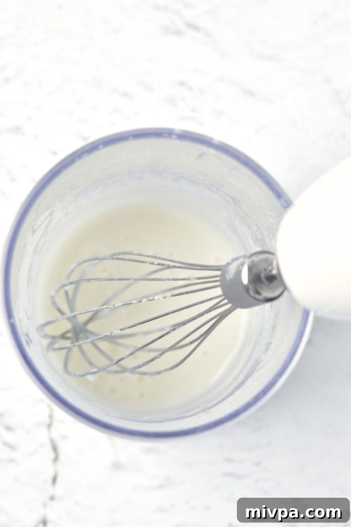 Icing for gingerbread men cookies Preparing icing in glass bowl, showing the smooth white mixture.