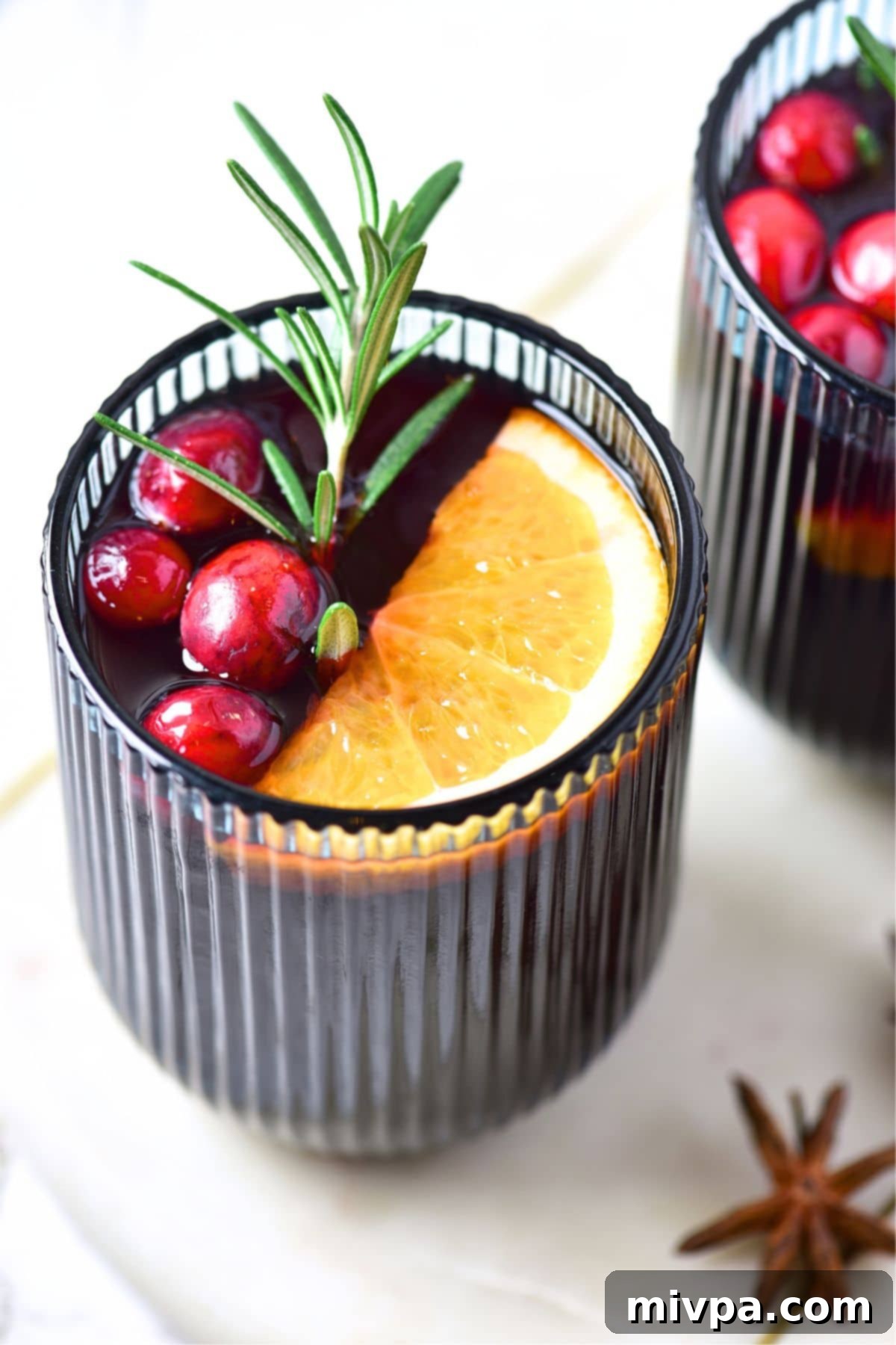 Simple Homemade Mulled Wine Gluten-Free and Vegan 3 Close-up of mulled wine simmering in a saucepan with orange slices and whole spices like star anise and cinnamon sticks.