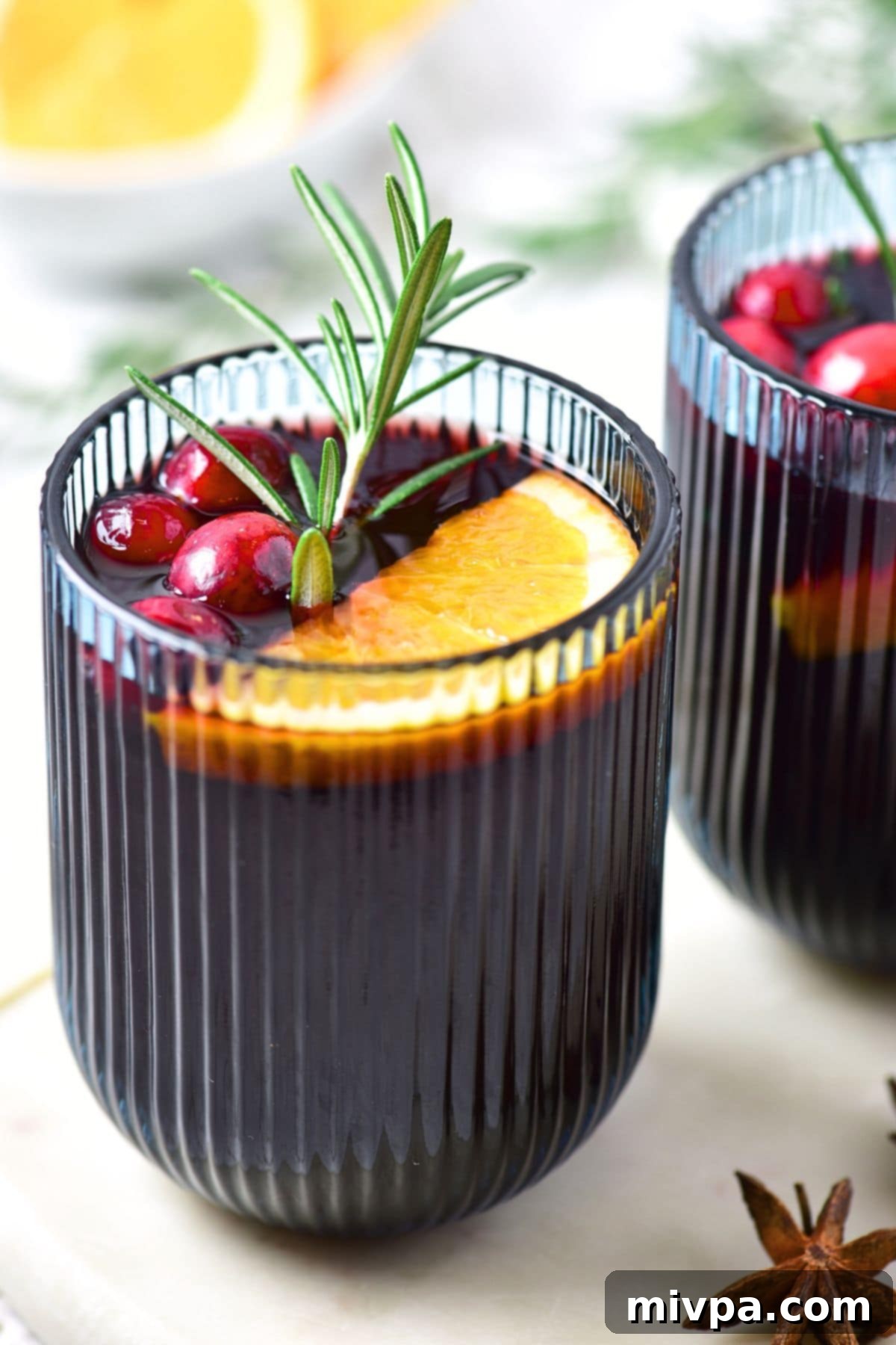 Simple Homemade Mulled Wine Gluten-Free and Vegan 4 Overhead view of mulled wine poured into a clear glass mug, with orange slices and whole spices visible at the bottom.