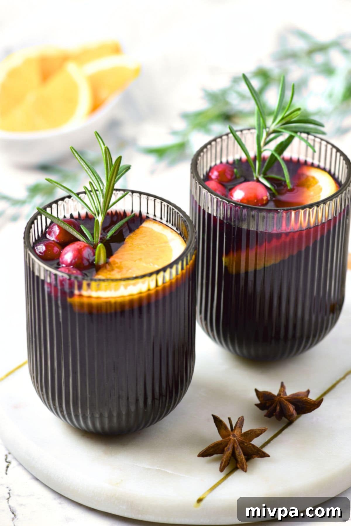 Simple Homemade Mulled Wine Gluten-Free and Vegan 9 Step 4: A beautifully garnished glass of mulled wine with fresh orange, cranberries, and a rosemary sprig, ready to be served.