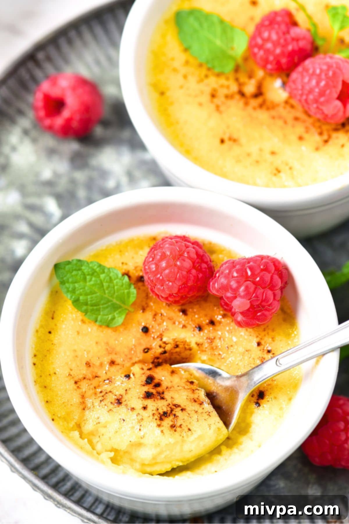 Two ramekins of perfectly torched crème brûlée, showcasing the golden-brown caramelized sugar crust and creamy custard beneath, ready to be served for a special occasion.