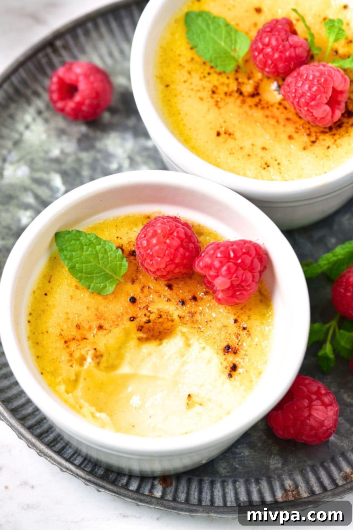 Three ramekins of crème brûlée, one with a spoon cracking the caramelized topping, arranged neatly on a wooden surface.