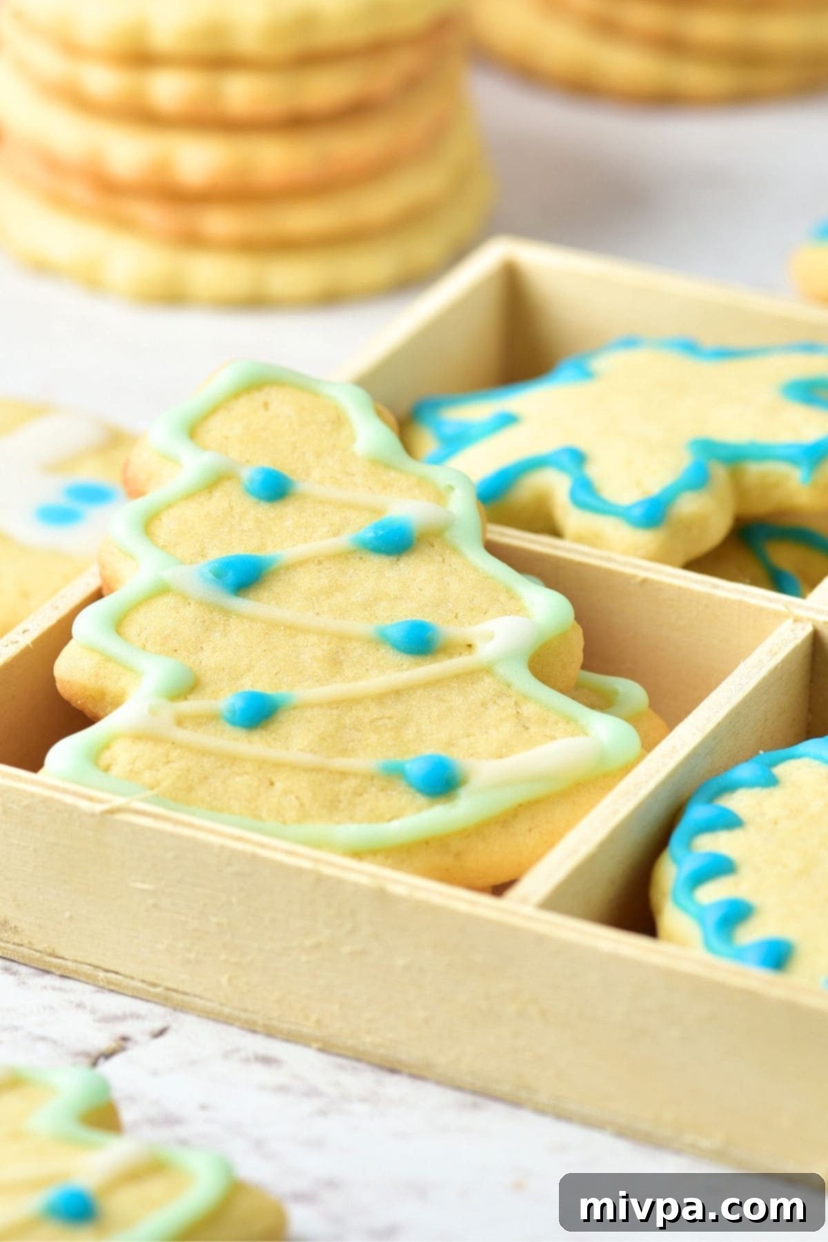 A rustic wooden box filled with an assortment of beautifully decorated gluten-free and dairy-free Christmas sugar cookies, featuring intricate icing designs in various festive colors.