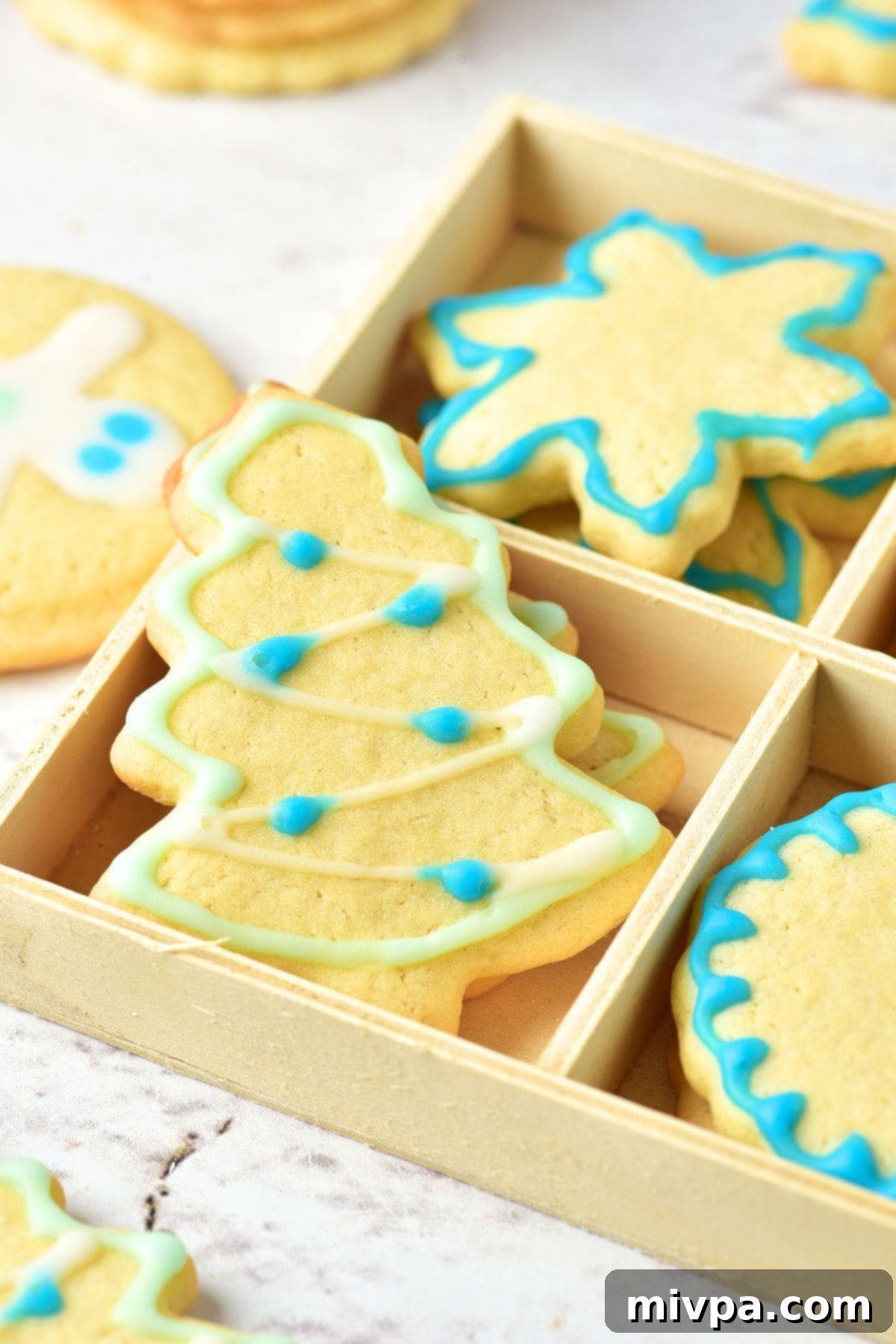 Christmas Cut-Out Sugar Cookies A box filled with various Christmas-themed cut-out sugar cookies, beautifully decorated with icing, ready for gifting.