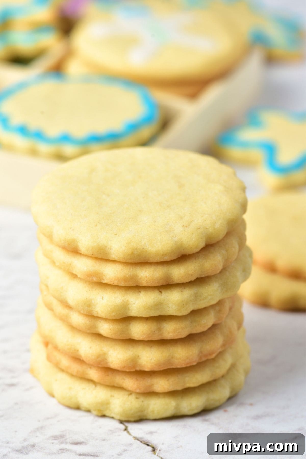 A charming stack of several gluten-free, dairy-free Christmas sugar cookies, each perfectly round and lightly golden, resting on a white marble board, awaiting decoration.