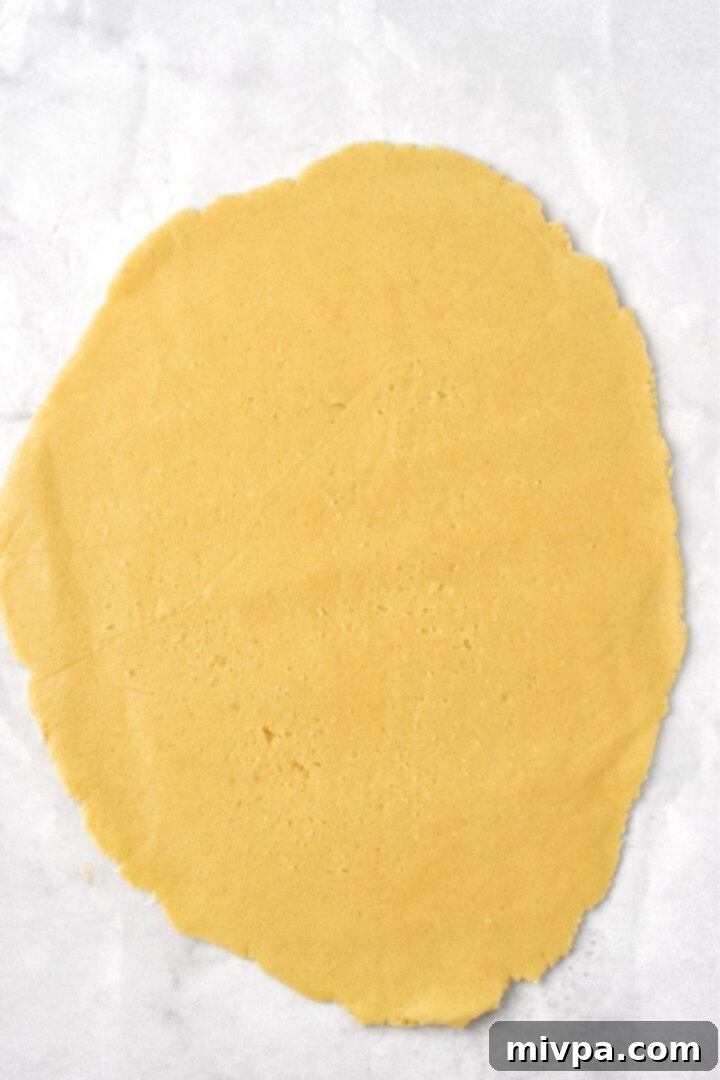Smooth, evenly rolled-out cookie dough sandwiched between two sheets of parchment paper, demonstrating the method for easy handling and consistent thickness.