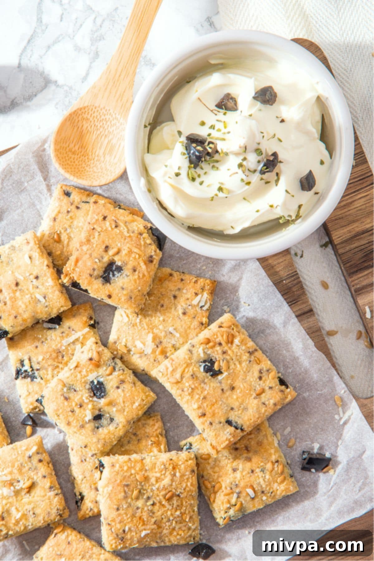 Almond Flour Crackers (Gluten-Free, Dairy-Free) Top down view of low carb crackers on parchment-lined wooden board.