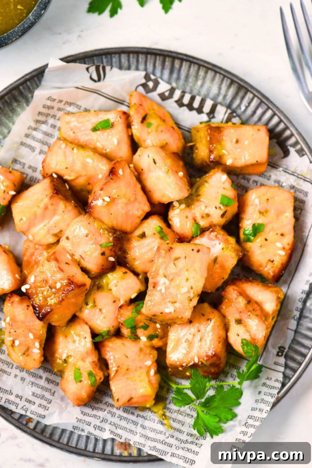 Top down view of a plate of air fryer salmon bites on parchment-lined plate.