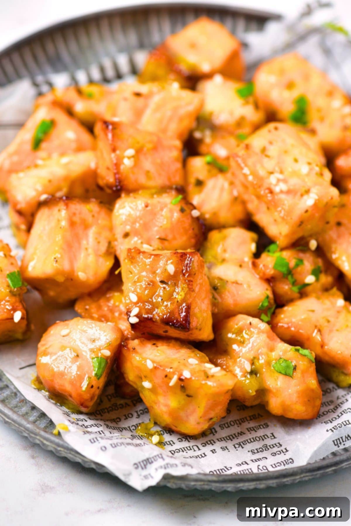 Up close view of salmon bites sprinkled with sesame seeds and chopped parsley