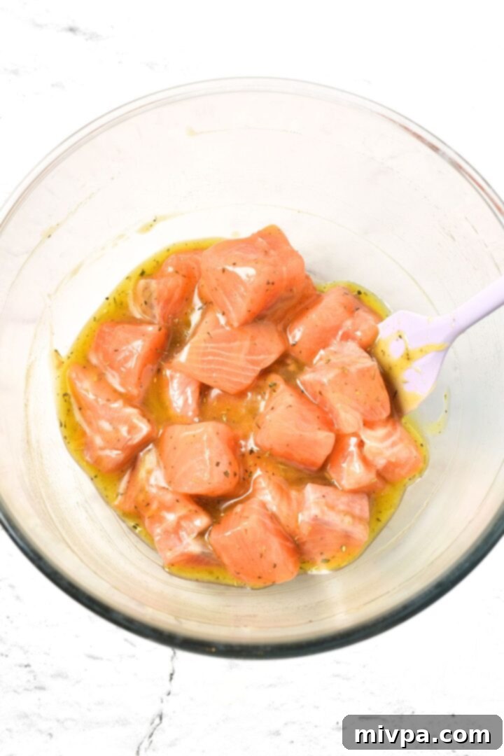 Marinated salmon cubes in glass mixing bowl
