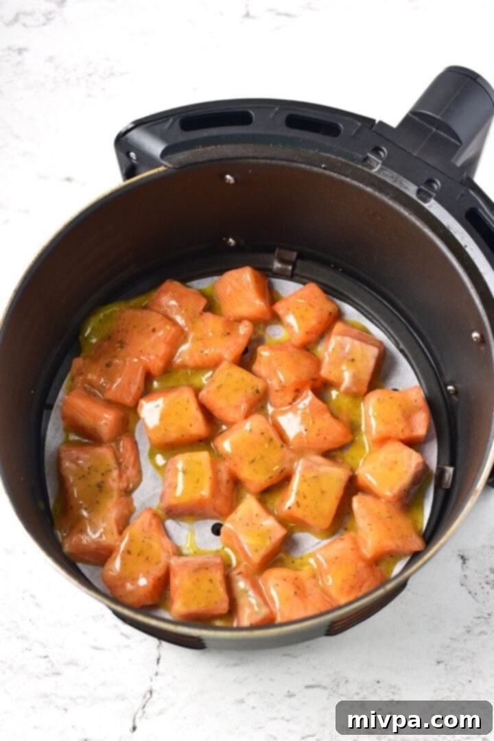 Salmon pieces in parchment-lined air fryer basket
