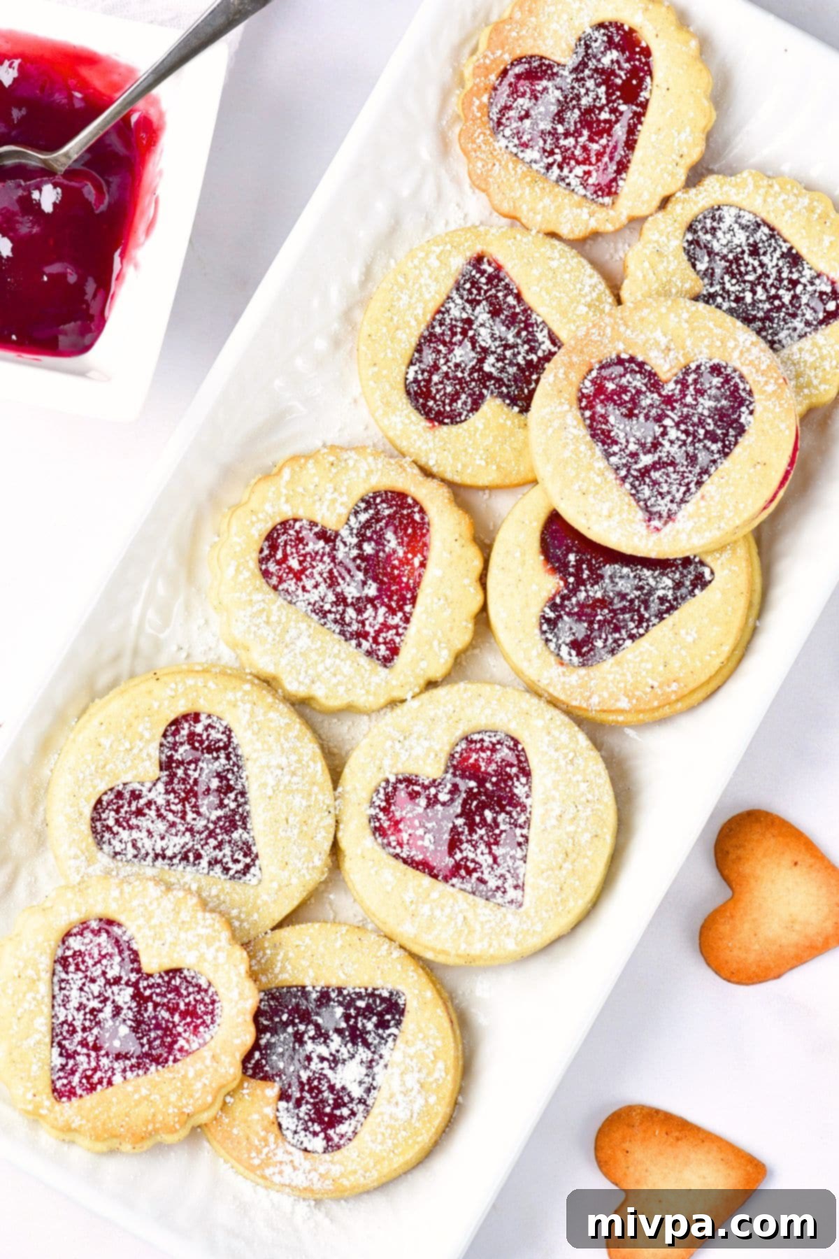 A plate of gluten-free Linzer cookies dusted in powdered sugar, ready for gifting or serving.