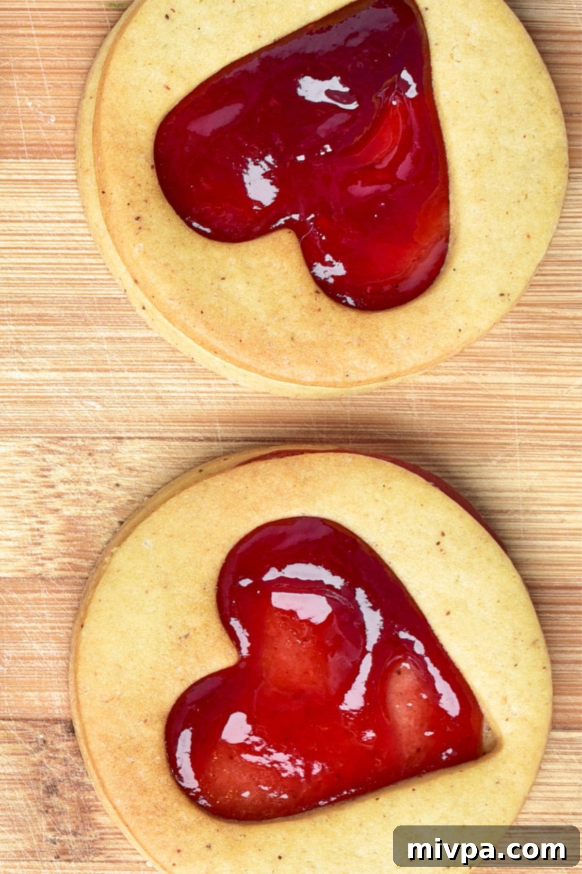 Assembling Linzer cookies with jam on a wooden board.
