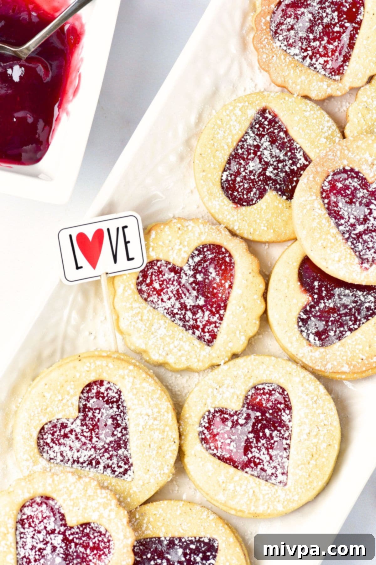 A plate of Linzer tart cookies generously sprinkled in confectioner's sugar.