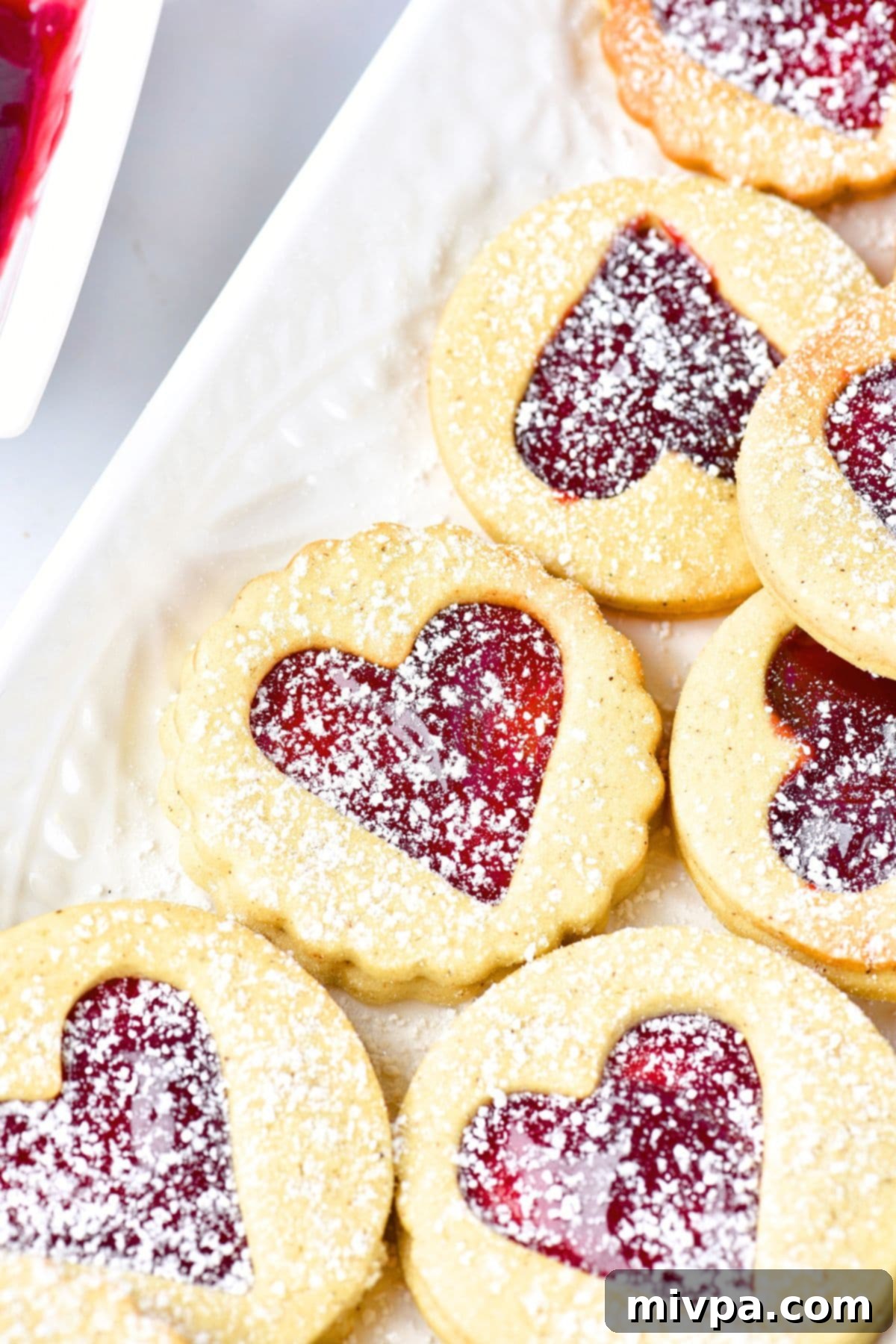 Up close view of a stack of gluten-free Linzer cookies with raspberry jam.