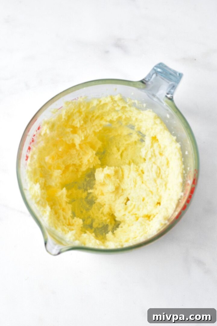 Pale yellow cookie dough in a measuring bowl after wet ingredients are combined.