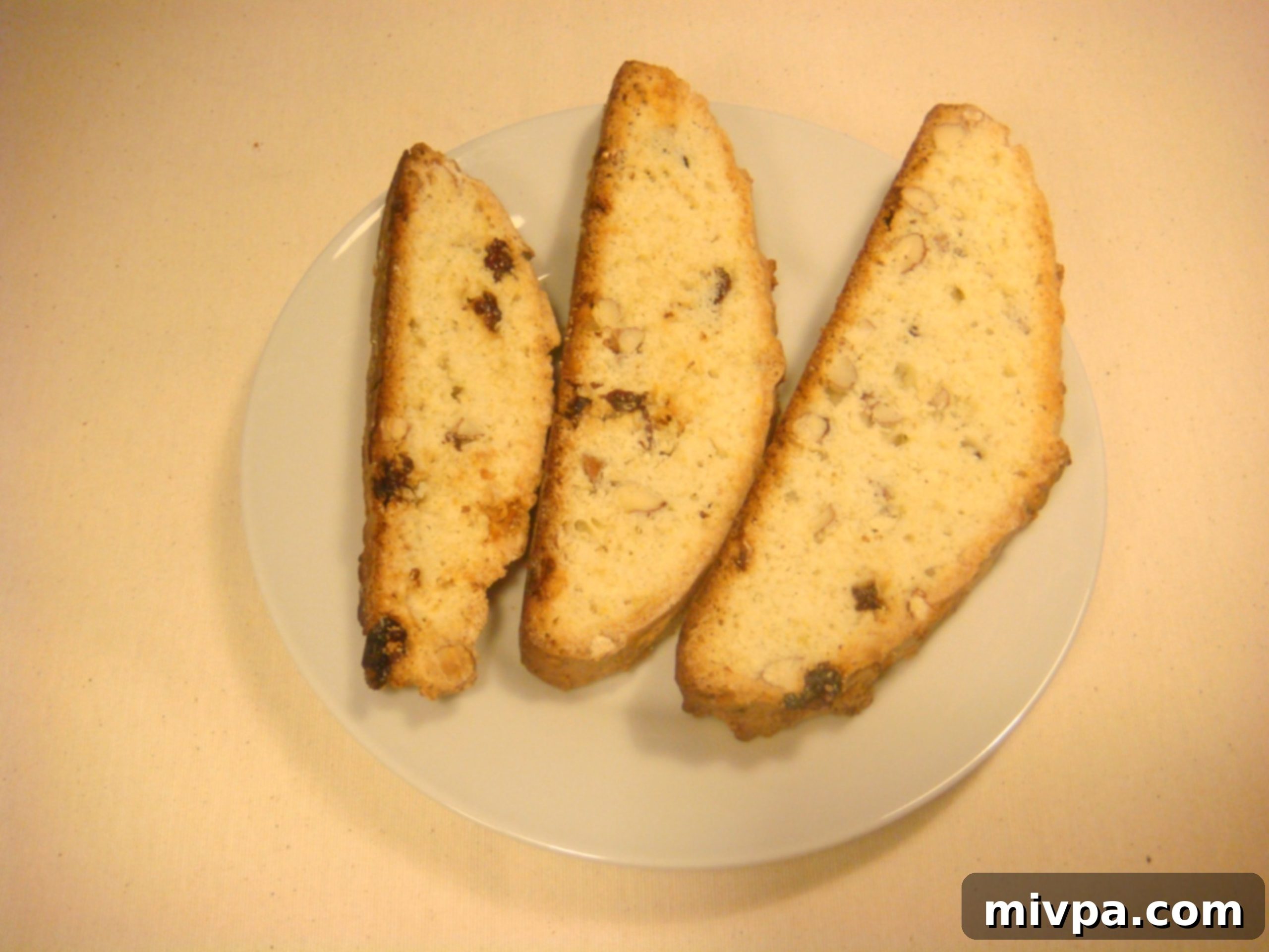 Zesty Lemon Almond Raisin Biscotti 2 A selection of freshly baked homemade biscotti, golden brown and perfectly crunchy, arranged artfully on a white plate, ready to be enjoyed.