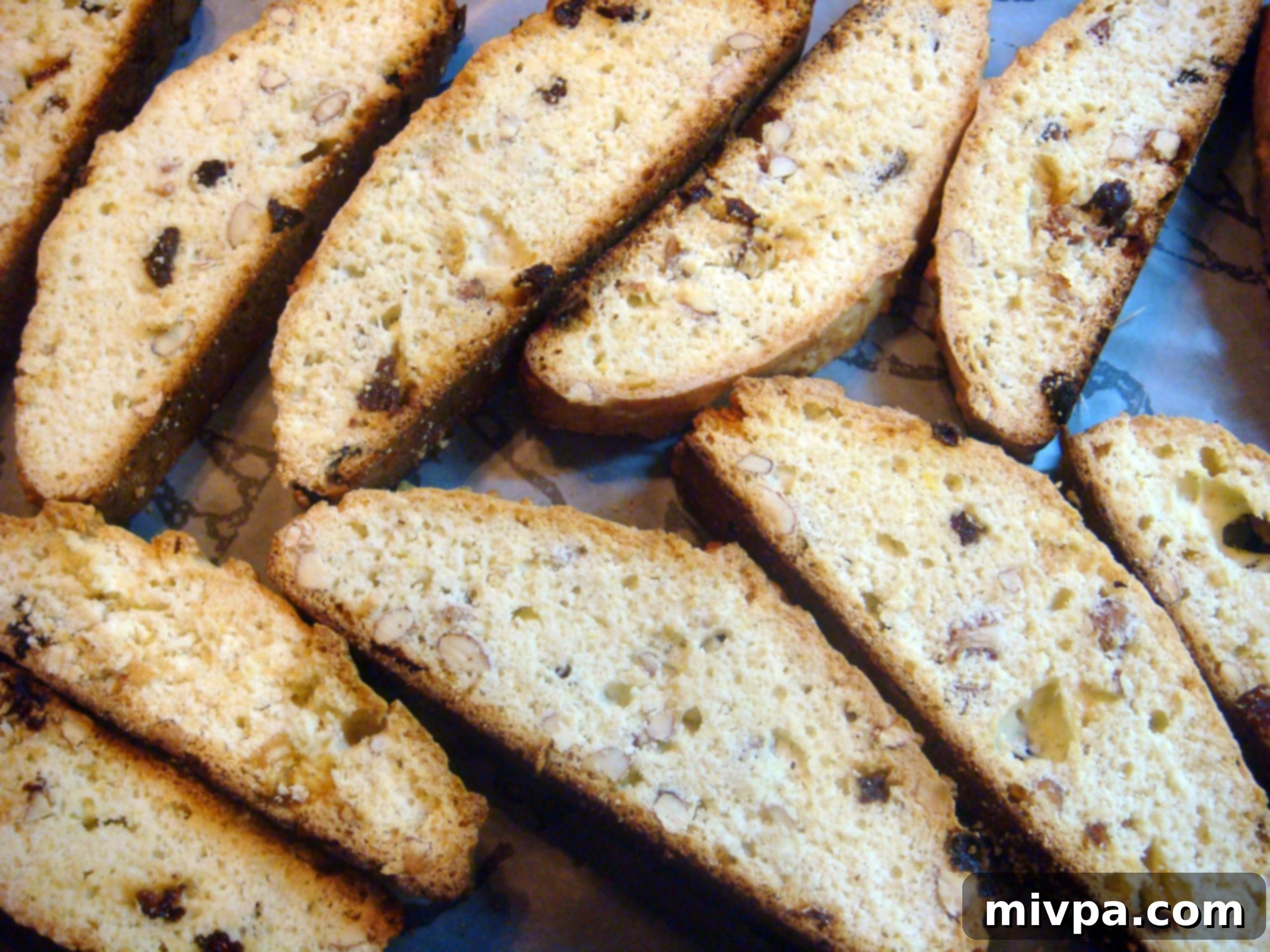 Zesty Lemon Almond Raisin Biscotti 3 A close-up view of golden-brown almond, raisin, and lemon biscotti, showing off their perfectly baked texture and inviting appearance.
