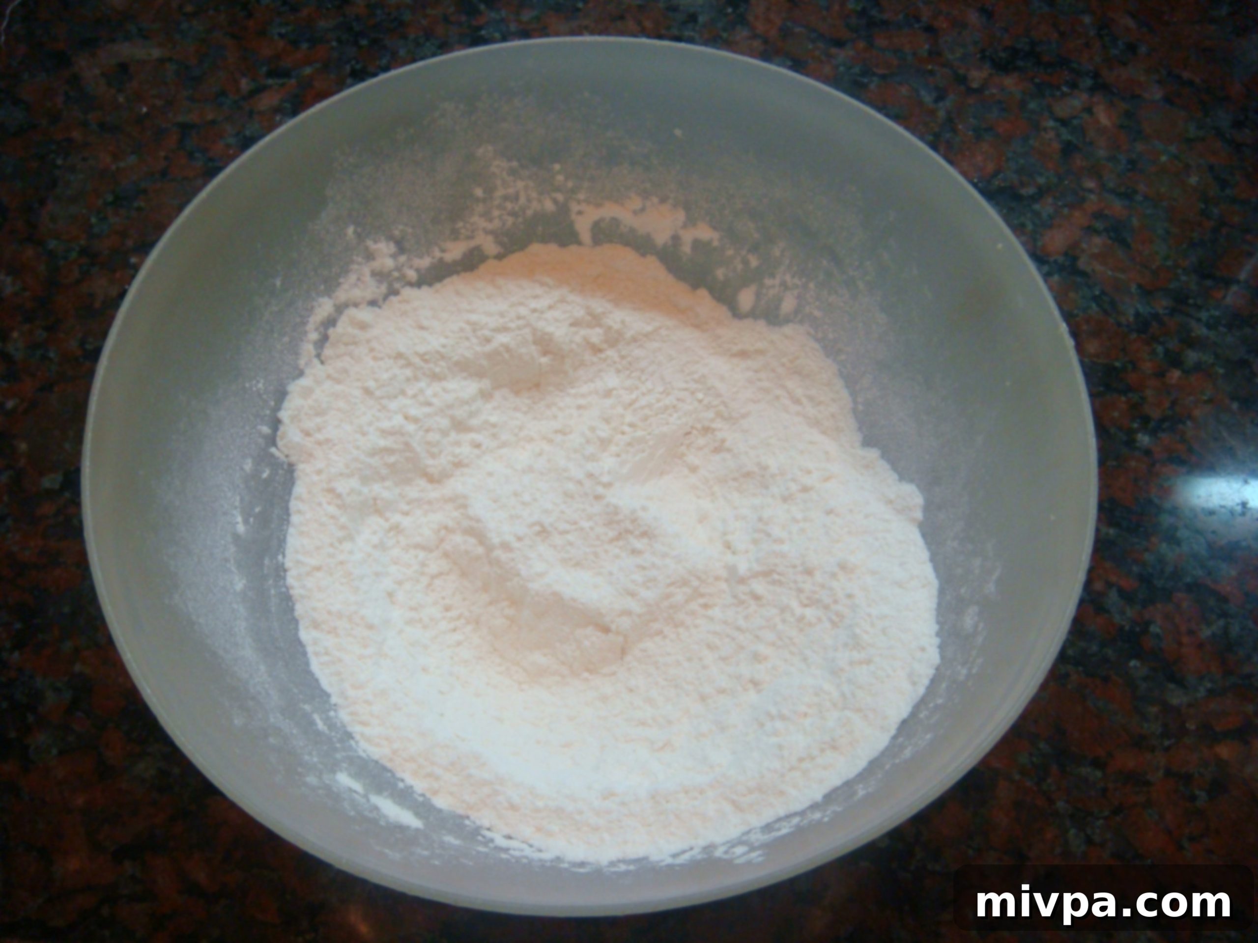 Zesty Lemon Almond Raisin Biscotti 4 Whisking flour, baking powder, and salt together in a white mixing bowl, ensuring even distribution of ingredients for the biscotti dough.