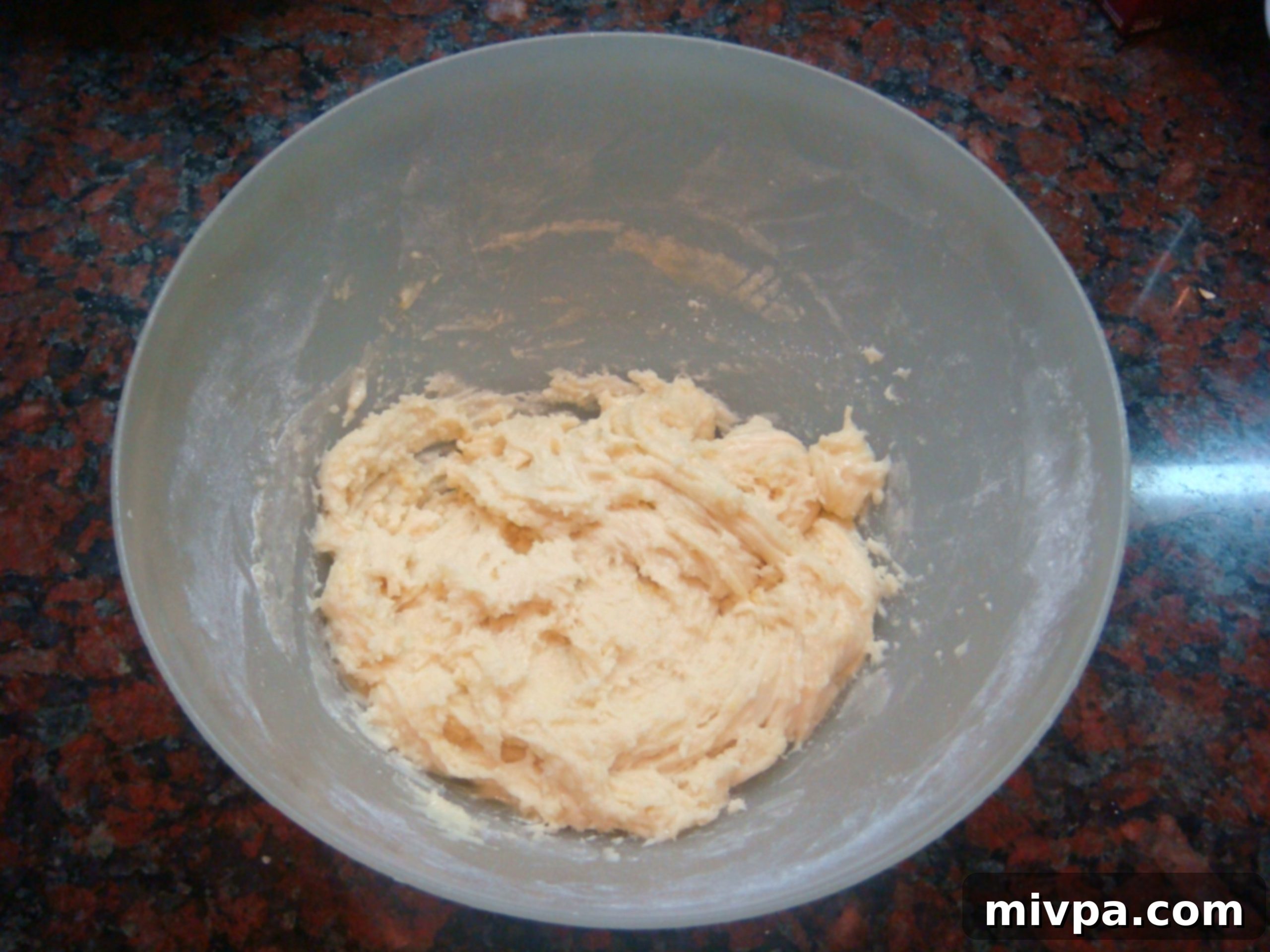 Zesty Lemon Almond Raisin Biscotti 8 The biscotti dough being beaten until all the flour and lemon zest are thoroughly blended into the wet ingredients, forming a cohesive mixture.
