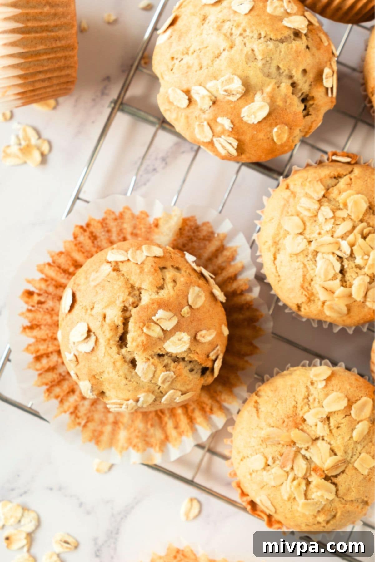 GF Oat Muffins Top down view of freshly baked oatmeal muffins cooling on a wire rack.