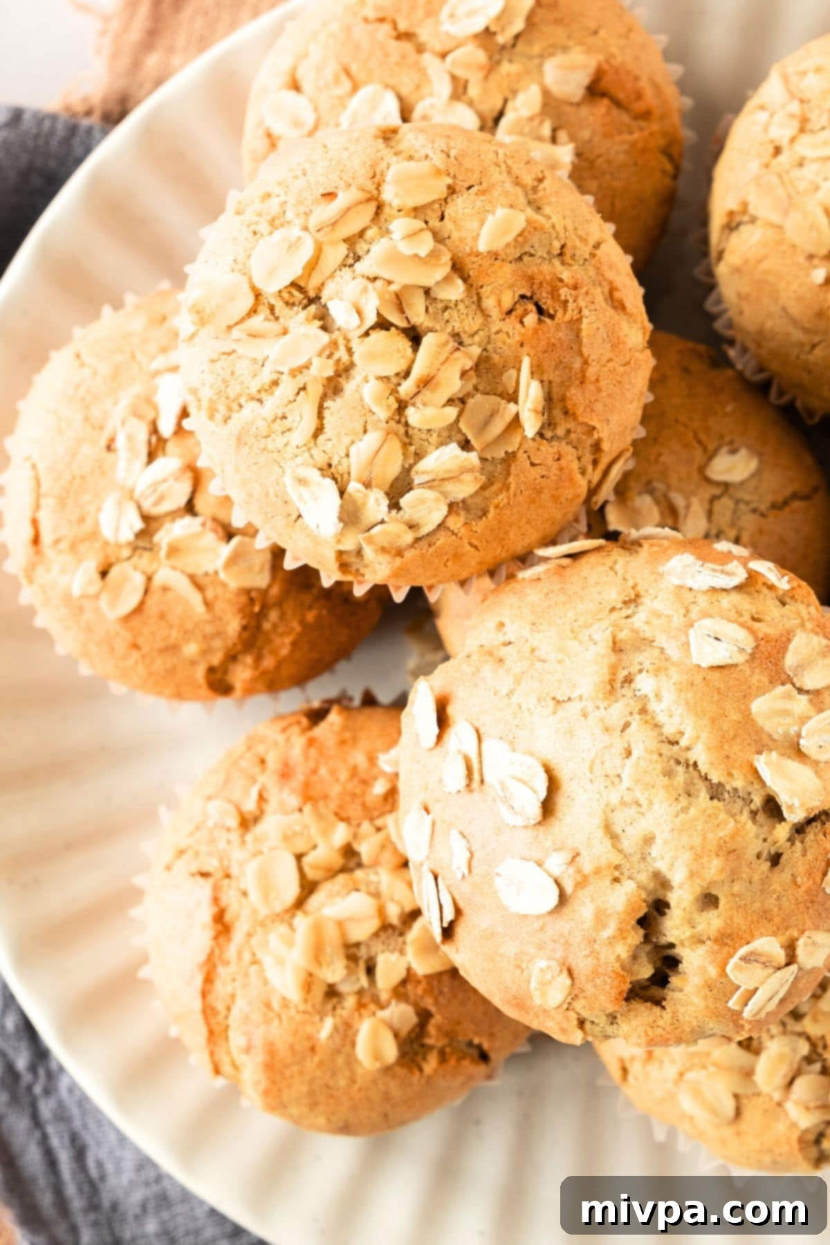 Oatmeal Muffins (Gluten-Free, Dairy-Free) Top down view of a plate with several gluten-free, dairy-free oatmeal muffins, garnished with extra oats.