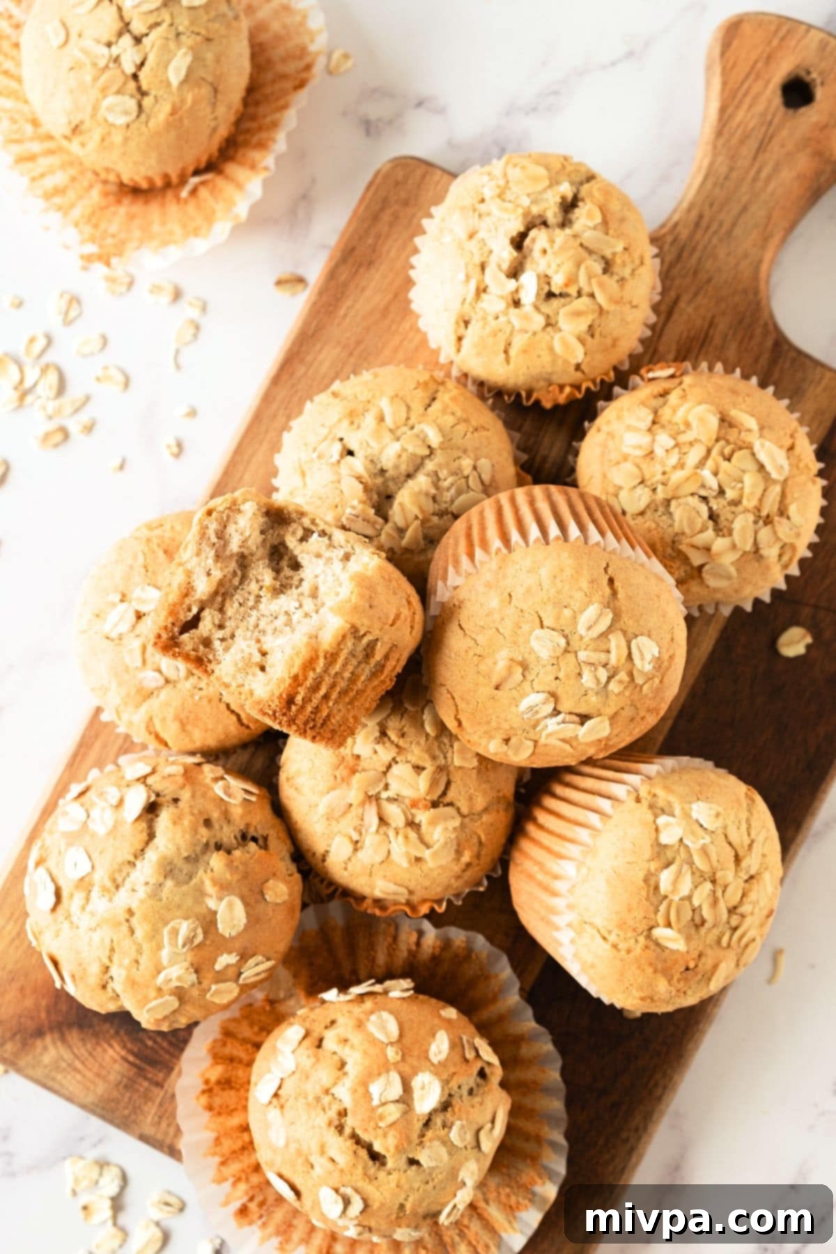 Oatmeal Gluten-Free Muffins (Dairy-Free) Top down view of freshly baked gluten-free oatmeal muffins on a rustic wooden board, ready to be enjoyed.