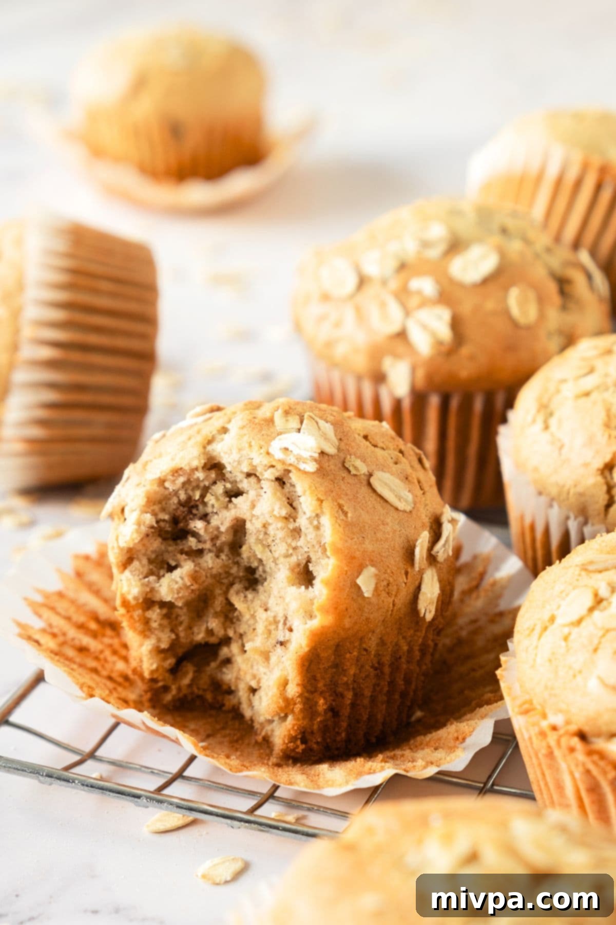 Gluten-Free Oat Muffins (Dairy-Free) Up close view of a half-eaten gluten-free oat muffin, showing its moist, tender interior and oat flecks.