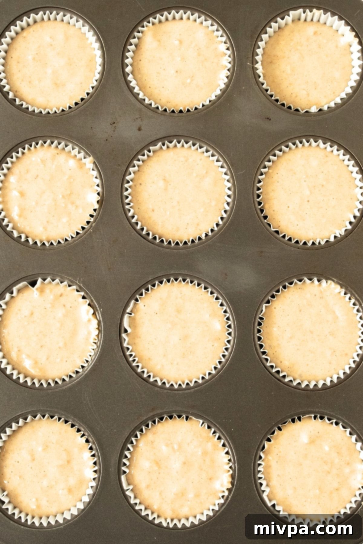 Easy Oatmeal Muffins (Gluten-Free) Muffin batter scooped into paper liners in a muffin tin, topped with additional rolled oats.