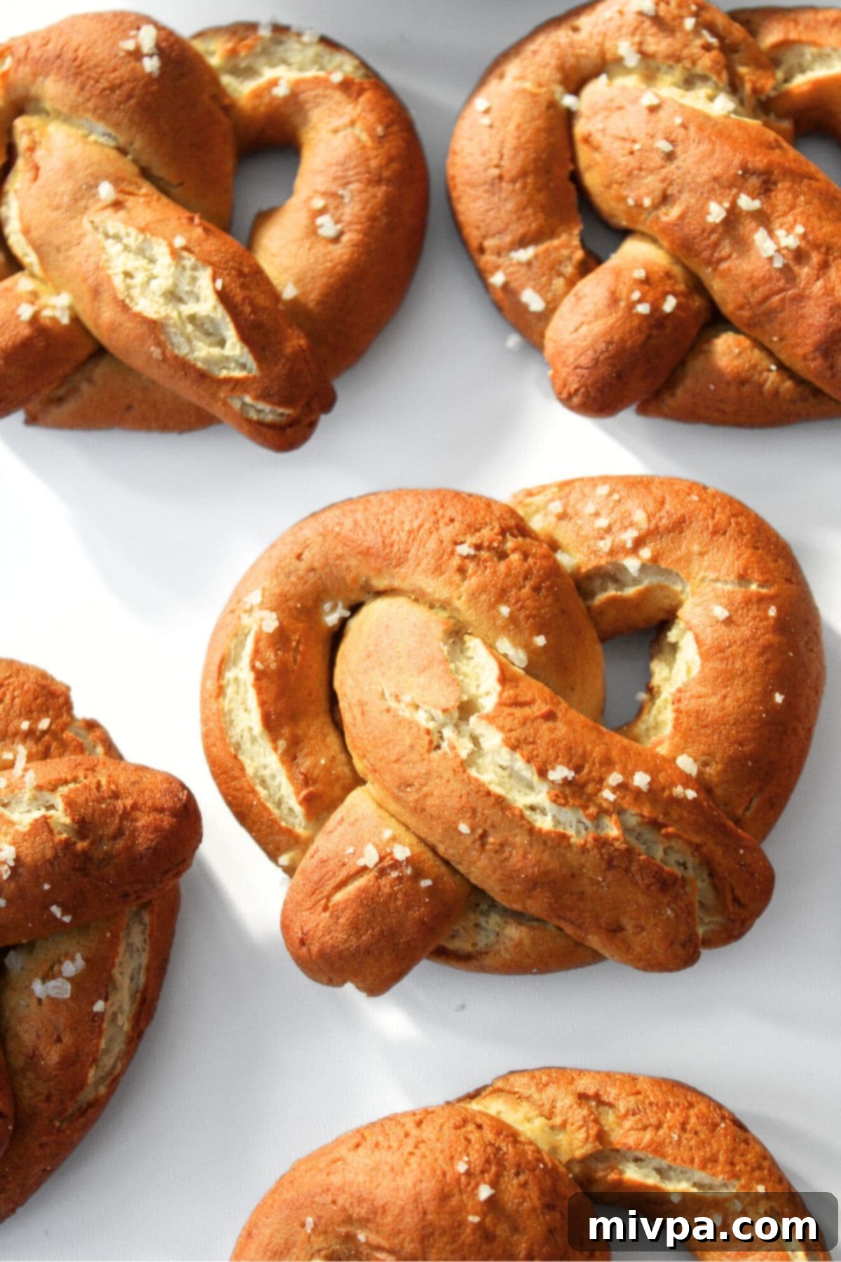 Freshly baked golden-brown gluten-free pretzels on parchment paper on a baking sheet, just out of the oven.