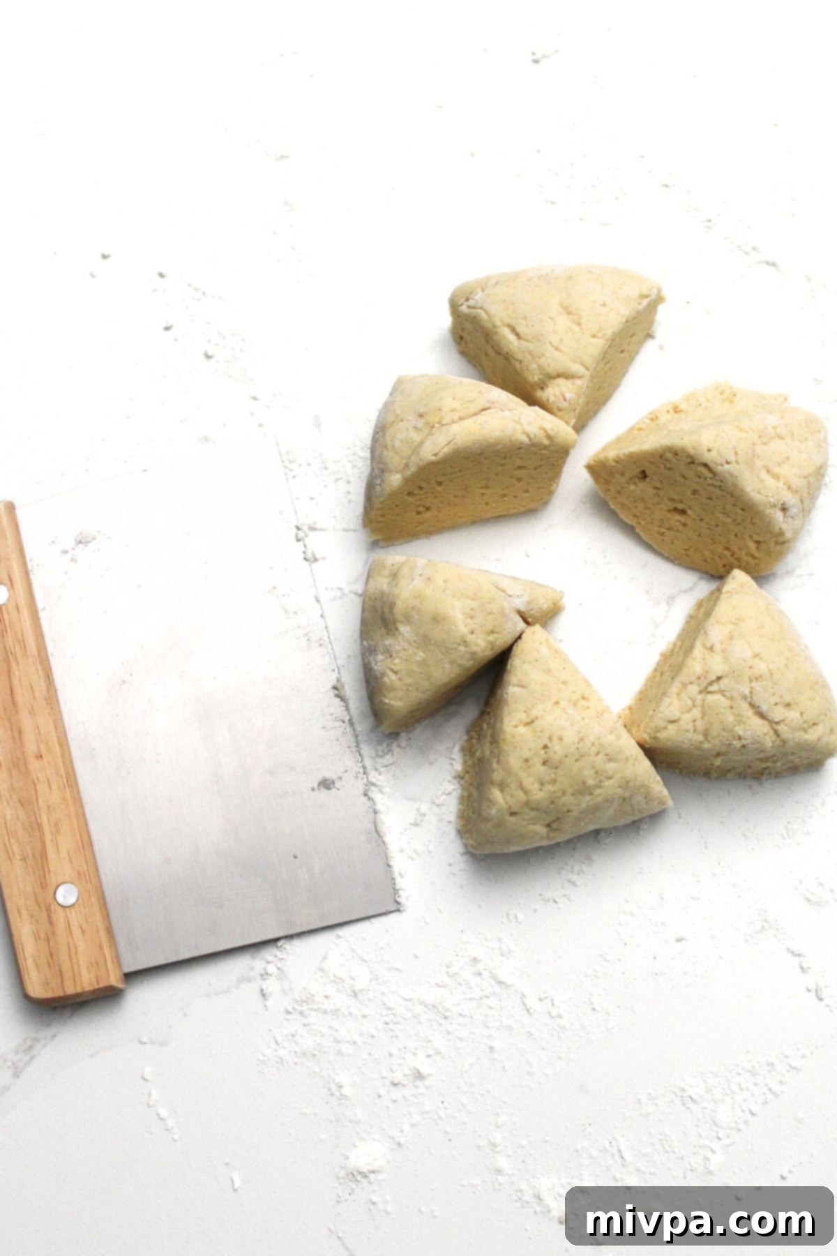 Pretzel dough, divided into six equal portions, neatly arranged on a white surface, ready for individual shaping.