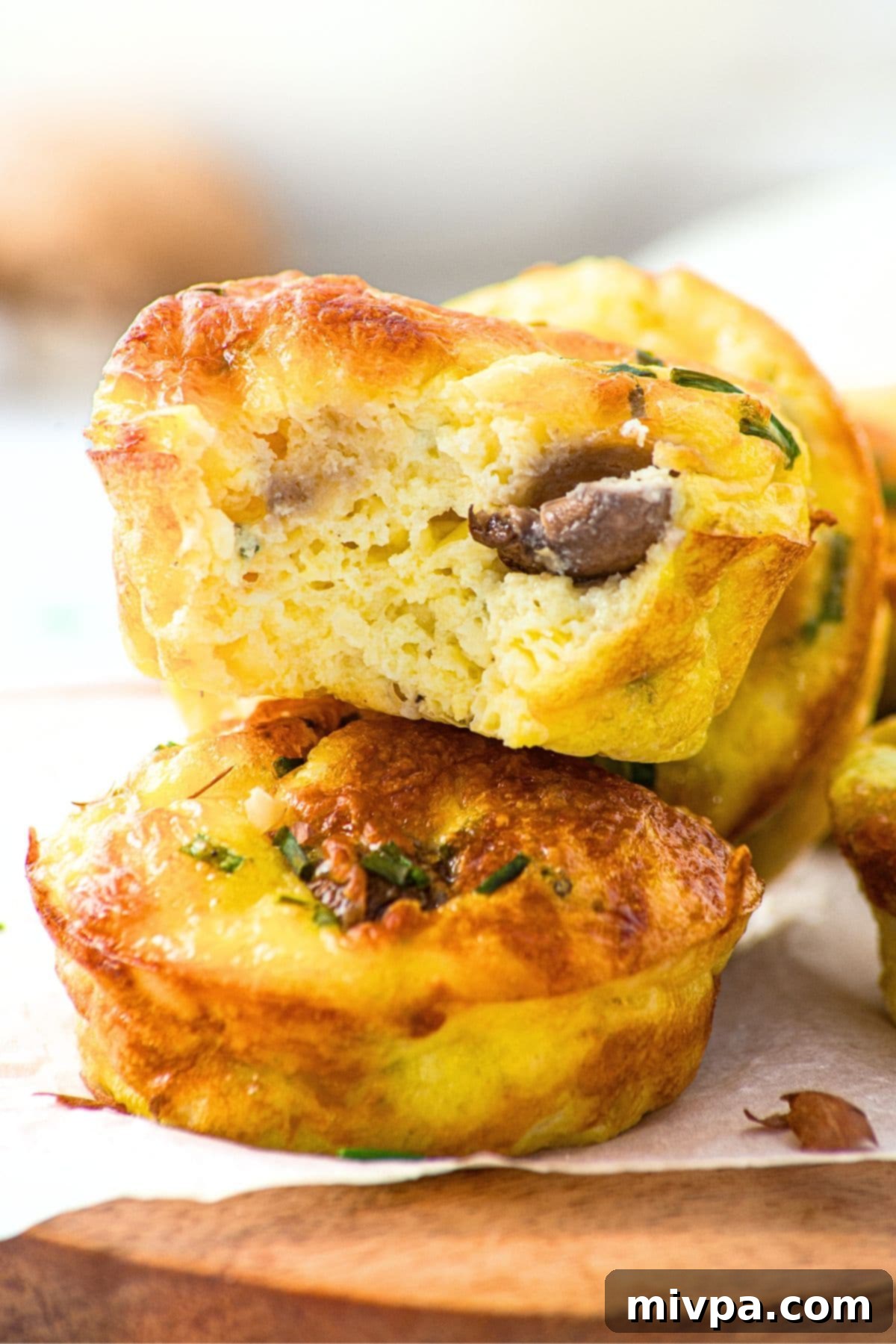 Egg Bites with Cottage Cheese (Gluten-Free) A half-eaten egg and cottage cheese muffin showing its moist interior, with other muffins in the background.