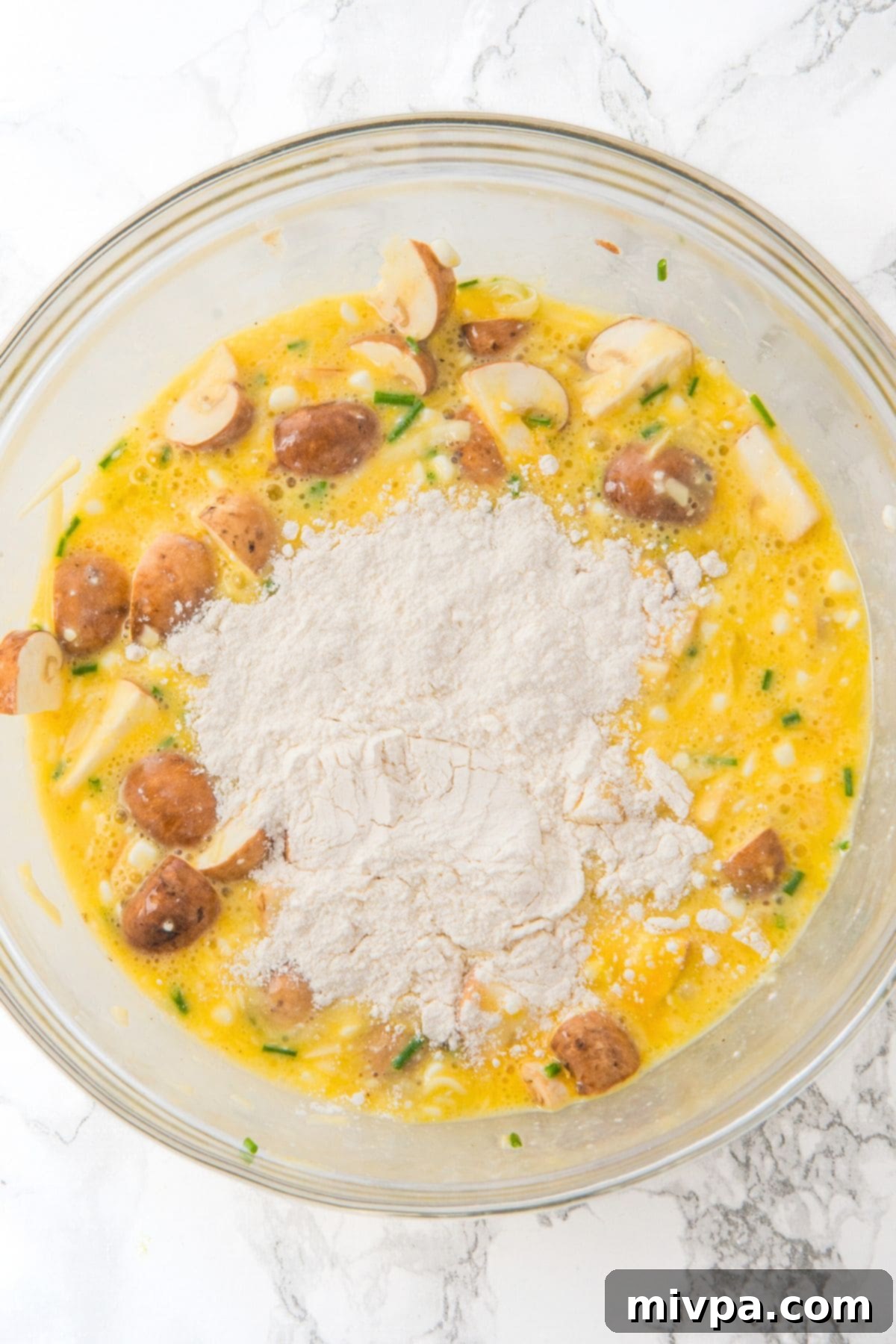 Gluten-Free Cottage Cheese and Egg Muffins Gluten-free flour lightly sprinkled on top of the egg and vegetable mixture, ready for mixing.