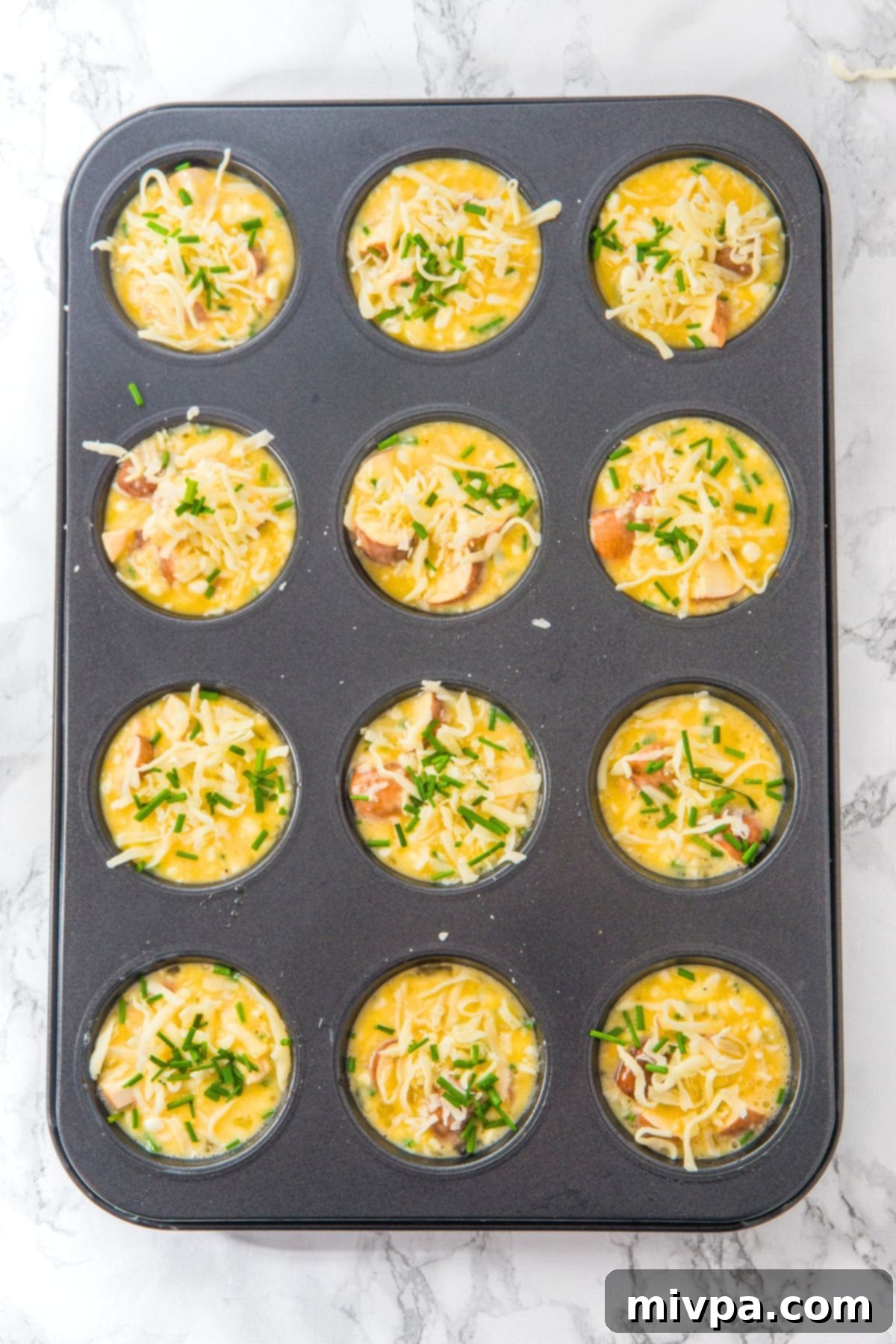 Cottage Cheese and Egg Muffins (Gluten-Free) Savory muffin batter carefully scooped into a well-greased muffin tin, ready for the oven.