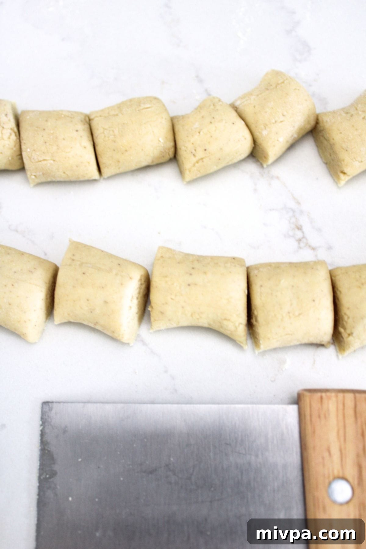 Cutting a long rope of pretzel dough into small, bite-sized pieces.