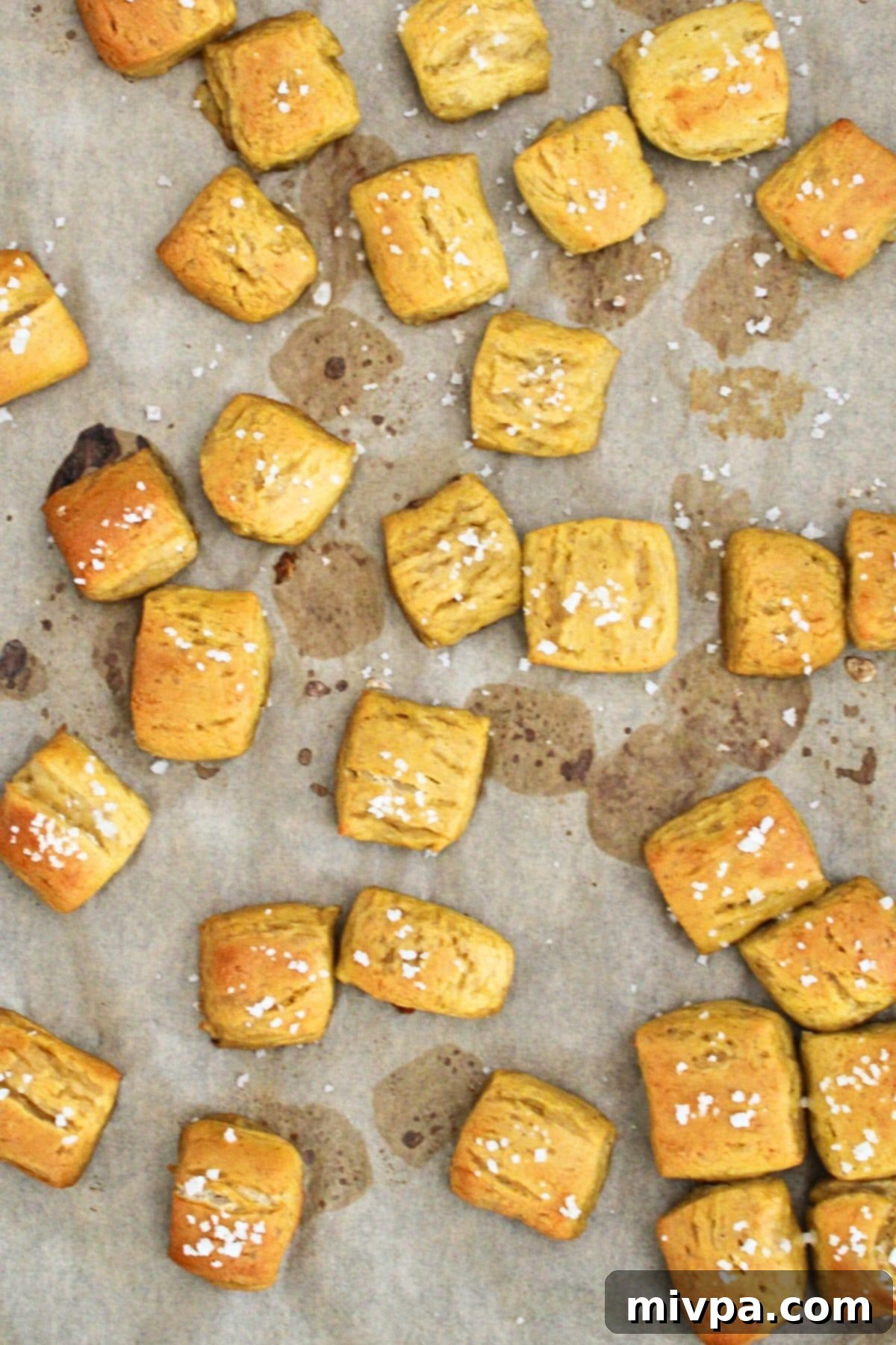 Freshly baked gluten-free pretzel bites cooling on parchment paper.