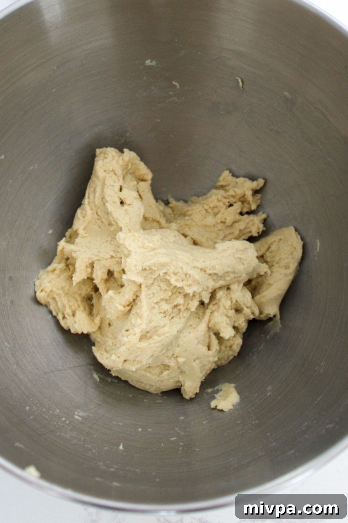 Pretzel dough forming a smooth ball in a metal mixing bowl.